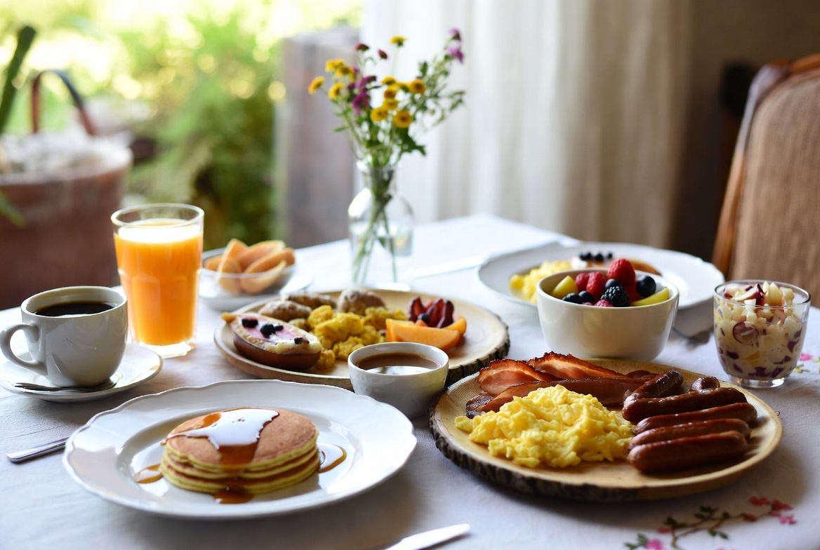 Breakfast and brunch table spread concept image with coffee, pancakes, fruit, and eggs